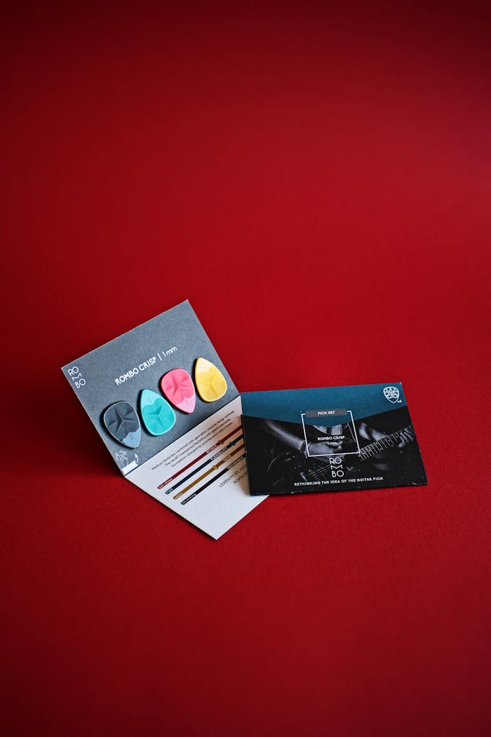 Close-up of vibrant guitar picks and cards on a striking red backdrop.